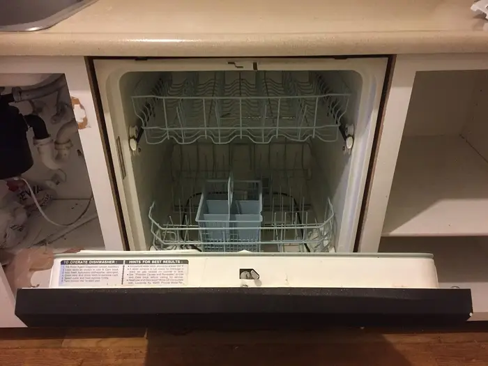 A built-in dishwasher with its door open under a kitchen worktop