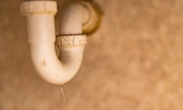 Water dripping from the trap under a bathroom sink