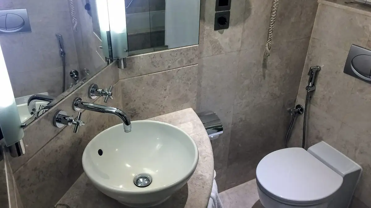 A modern bathroom with a vessel basin, wall tap and toilet