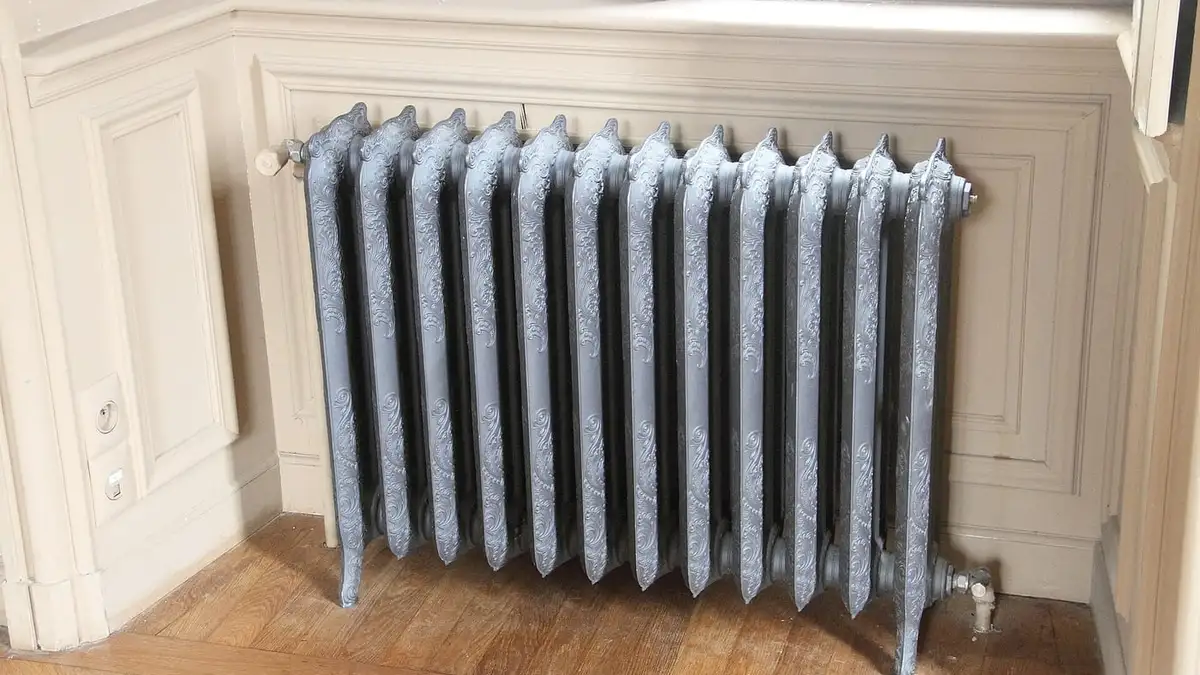 A cast iron column radiator under a window in a panelled room