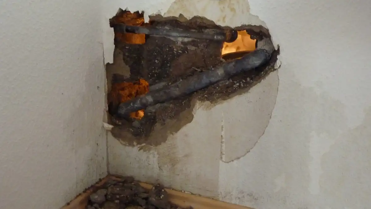 A wall opened up to expose a burst water pipe