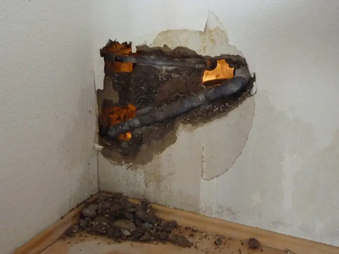 A wall opened up to expose a burst water pipe
