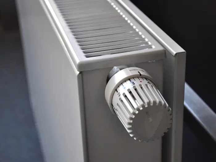 A thermostatic valve on the side of a white panel radiator
