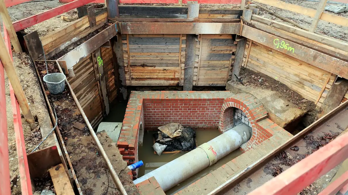 A new drain pipe and brick chamber in a shored excavation
