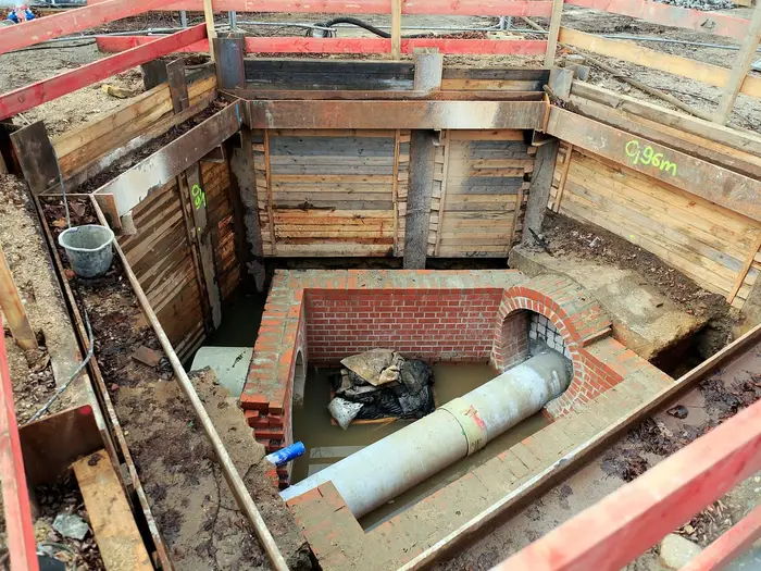A new drain pipe and brick chamber in a shored excavation