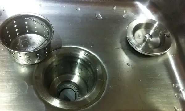 A stainless steel kitchen sink waste outlet with its basket strainer and plug removed