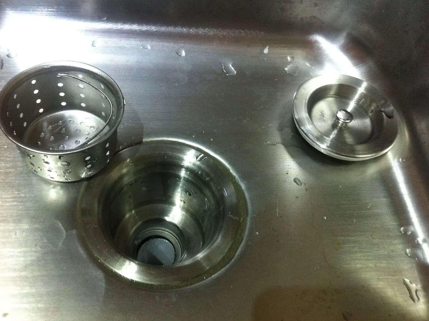 A stainless steel kitchen sink waste outlet with its basket strainer and plug removed
