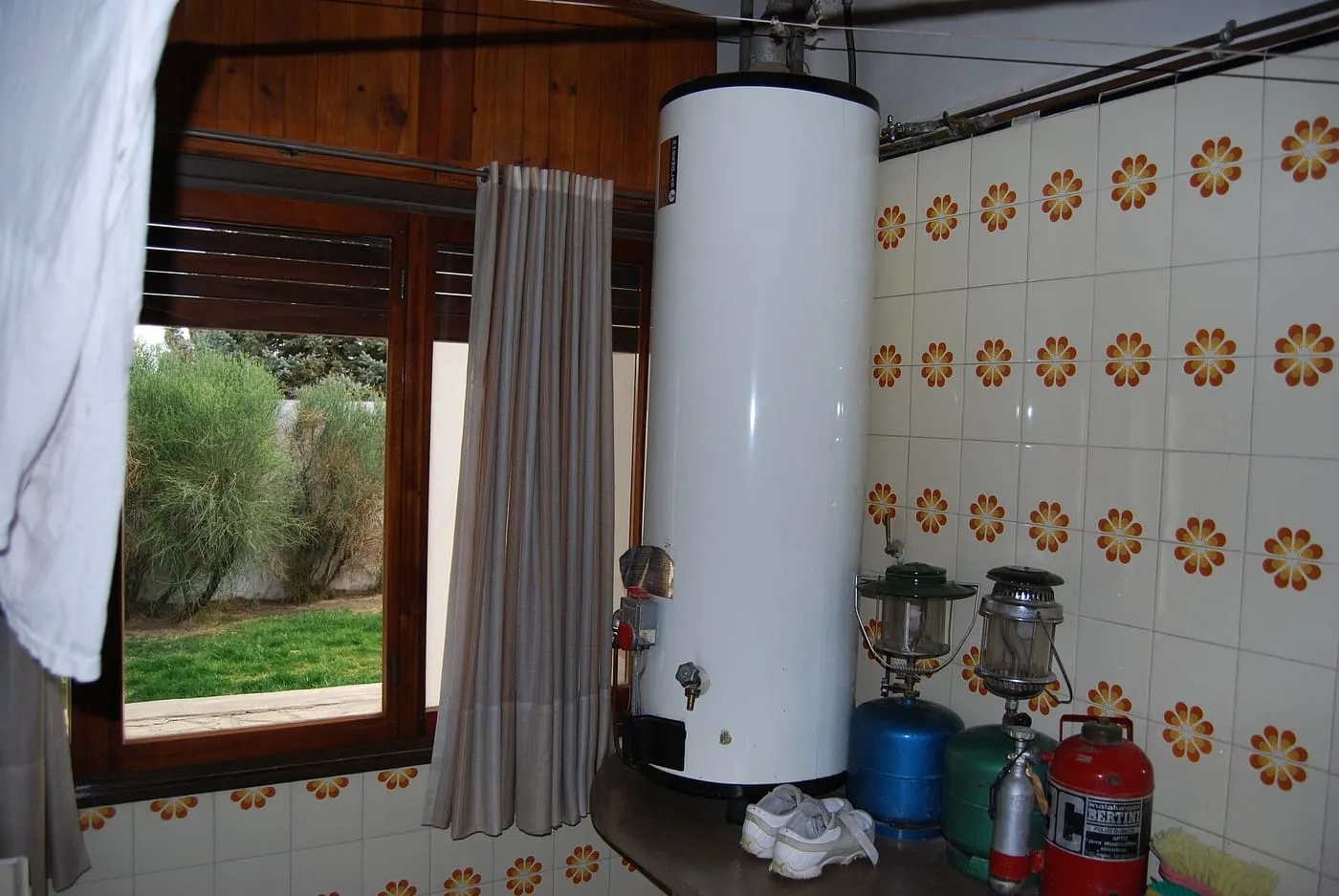 A tall white hot water storage tank standing in a tiled room