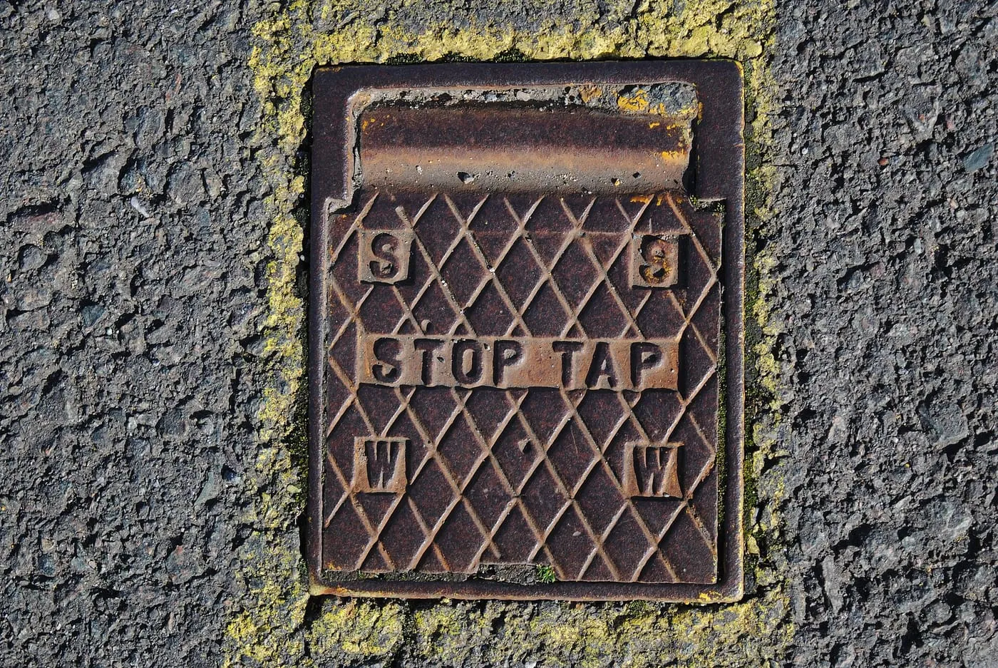 A cast iron stop tap cover set into a pavement