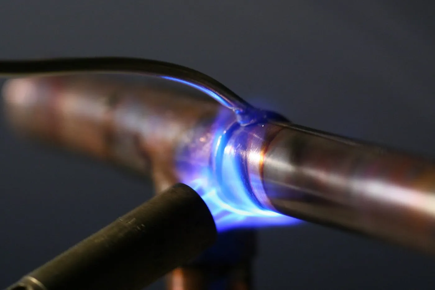 A blue torch flame soldering a joint on copper pipe