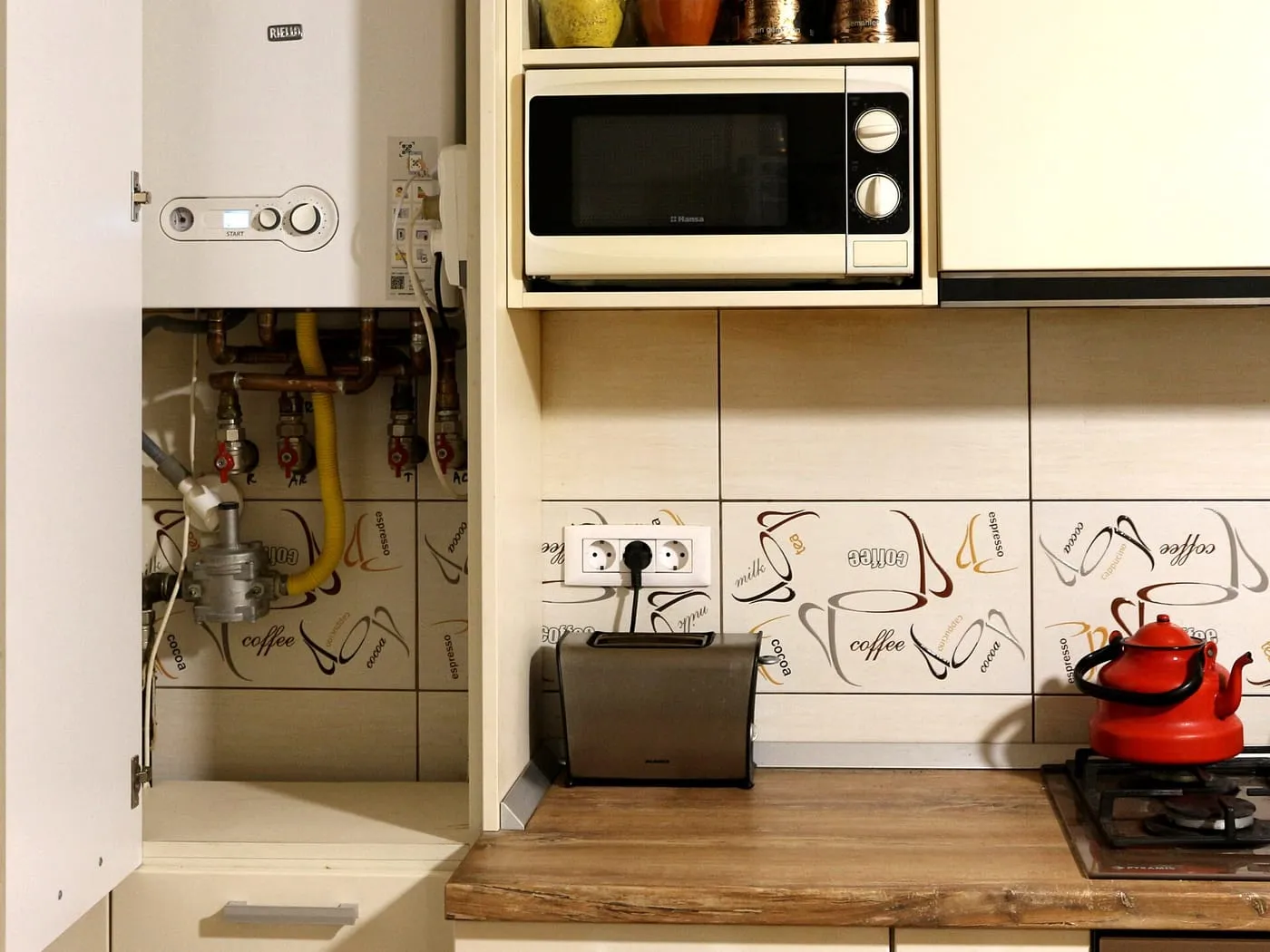 A wall-mounted boiler fitted in a kitchen cupboard beside a microwave