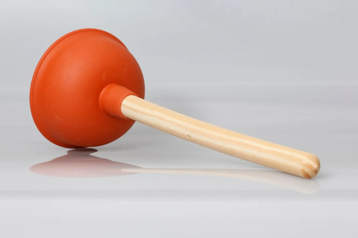 A rubber sink plunger with a wooden handle