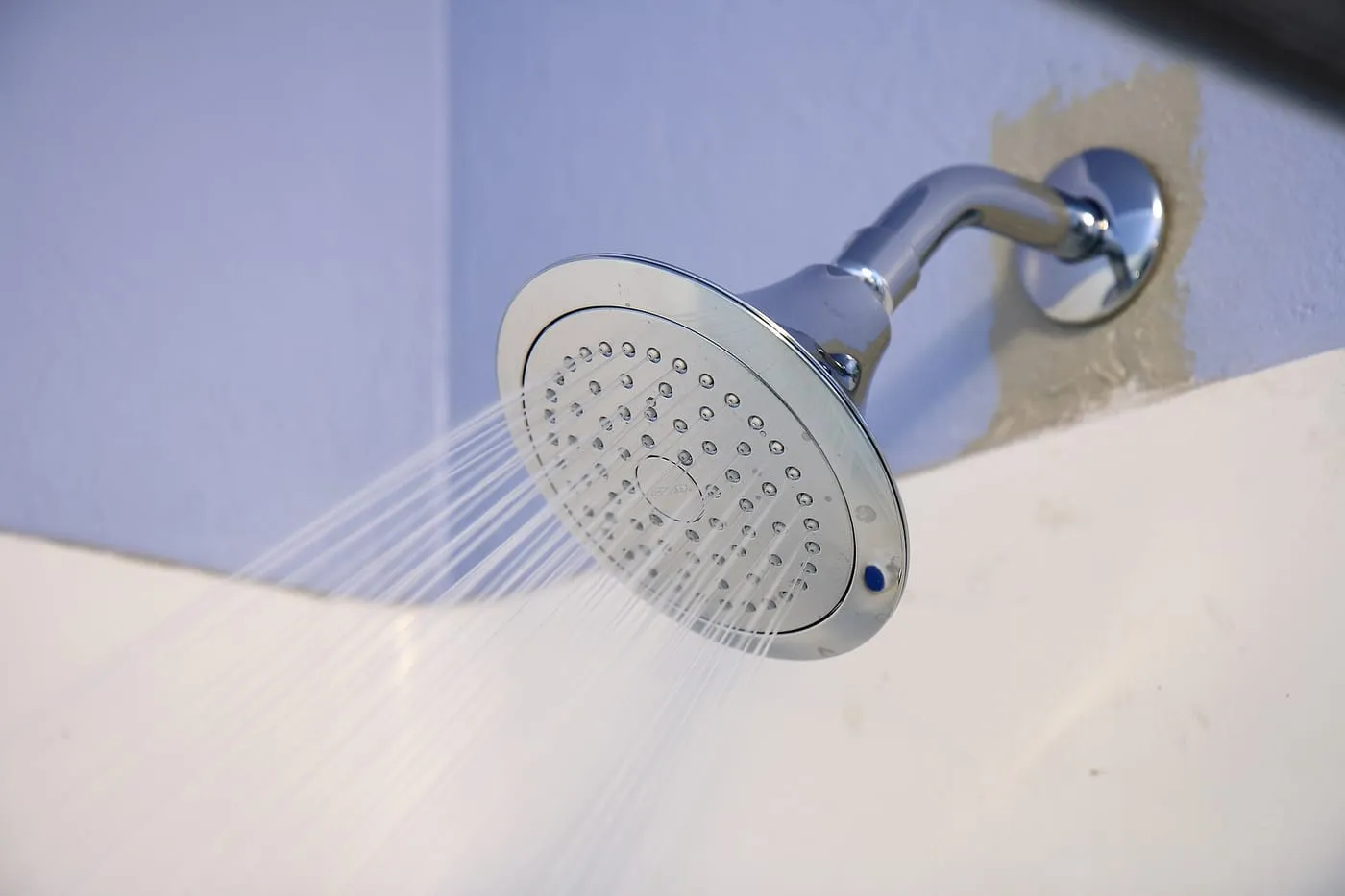 A chrome shower head spraying water
