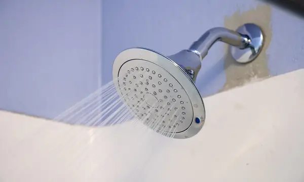 A chrome shower head spraying water