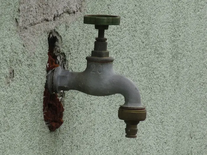 An old metal tap on an outside wall