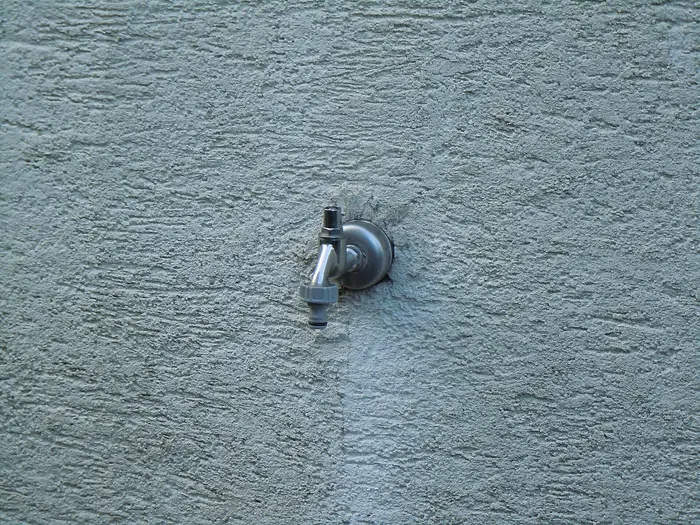 An outside tap fixed to a rendered house wall