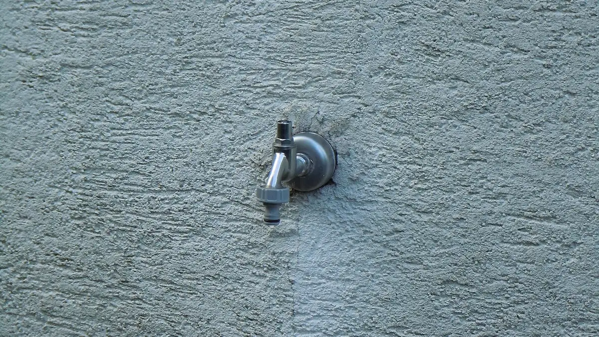 An outside tap fixed to a rendered house wall