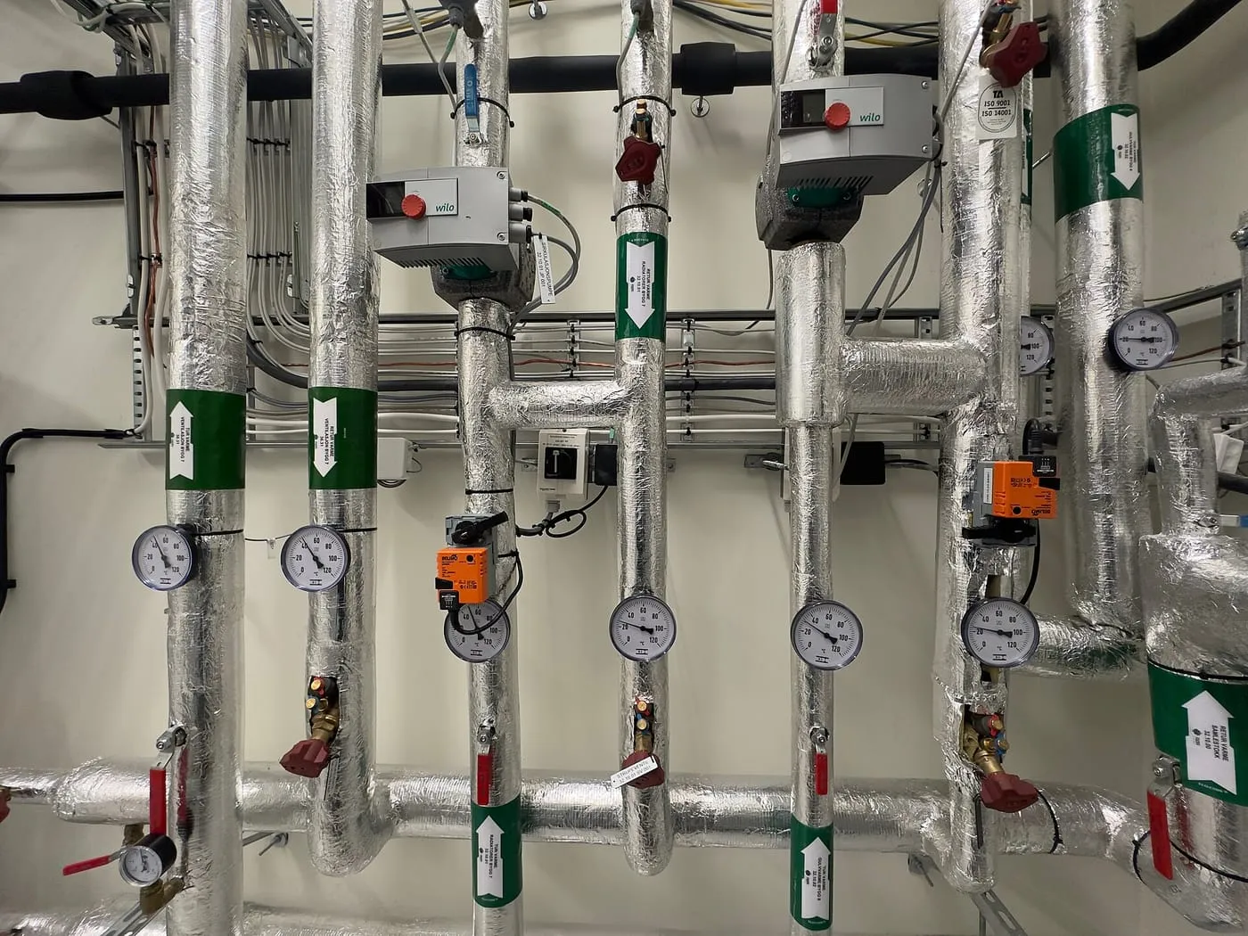 Insulated pipework with gauges and valves in a plant room