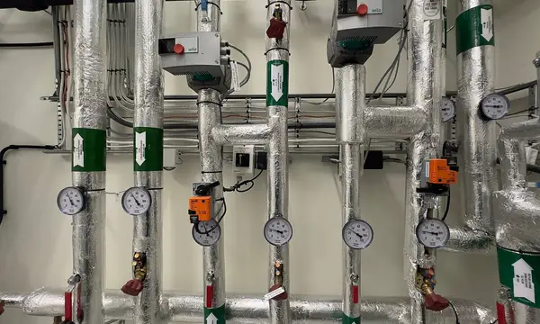 Insulated pipework with gauges and valves in a plant room