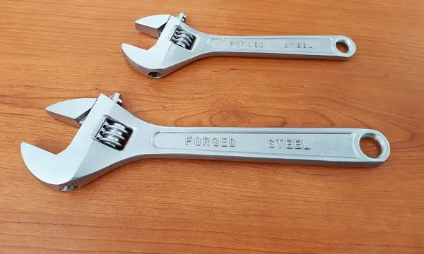 Two adjustable spanners on a wooden surface
