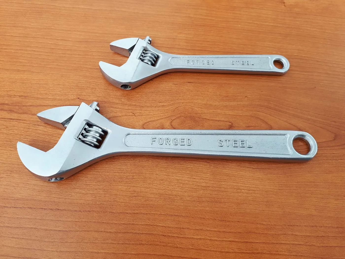 Two adjustable spanners on a wooden surface