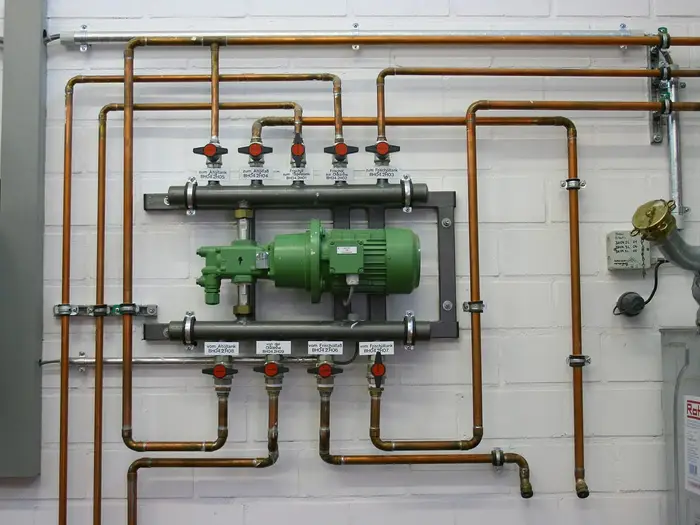 A heating manifold and circulating pump on copper pipework against a white wall