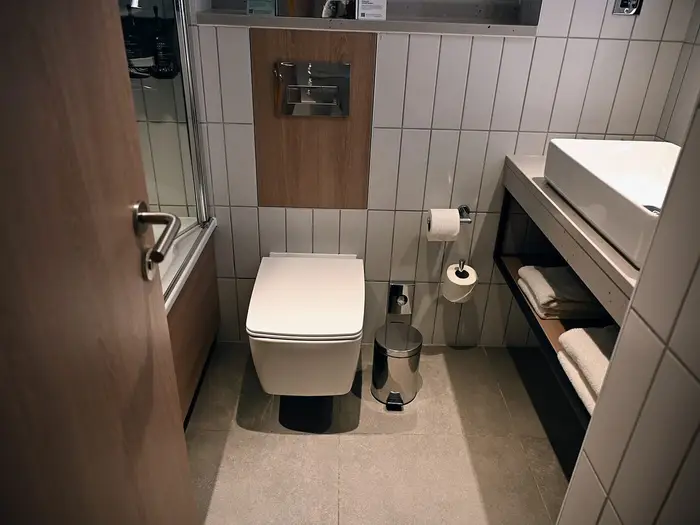 A compact toilet room with a wall-hung toilet beside a vanity unit