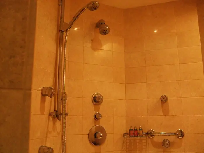 A tiled shower with a riser rail, body jets and thermostatic controls