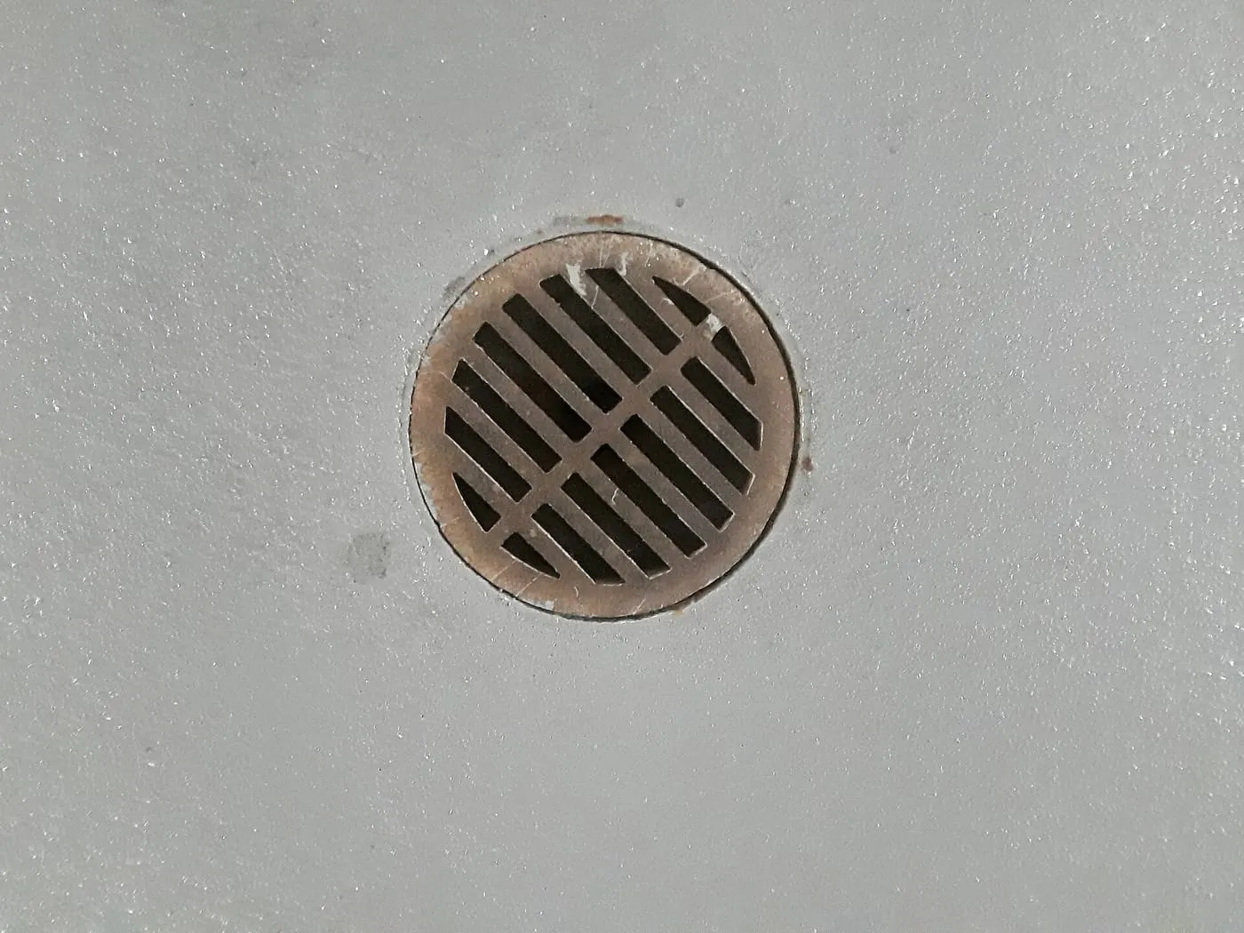 A round floor drain grate in a concrete floor