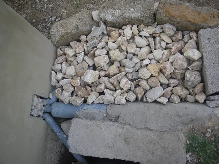 A soakaway pit filled with stones, with the inlet pipe below