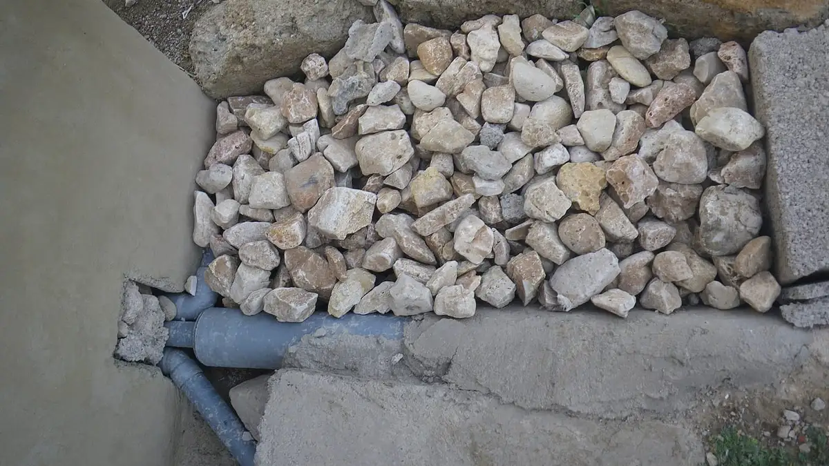 A soakaway pit filled with stones, with the inlet pipe below