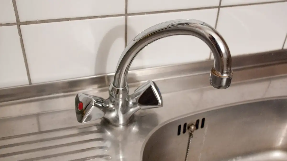 A chrome swan-neck mixer tap over a stainless steel kitchen sink