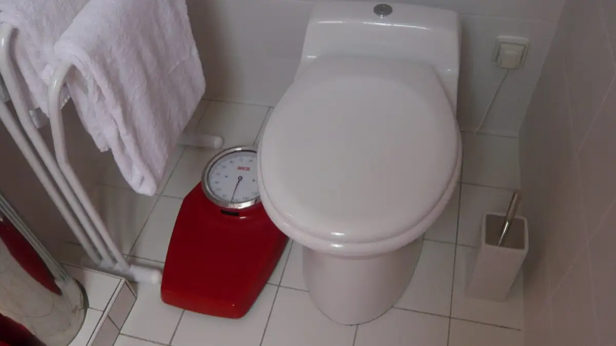 A white close-coupled toilet in a tiled bathroom beside a towel rail