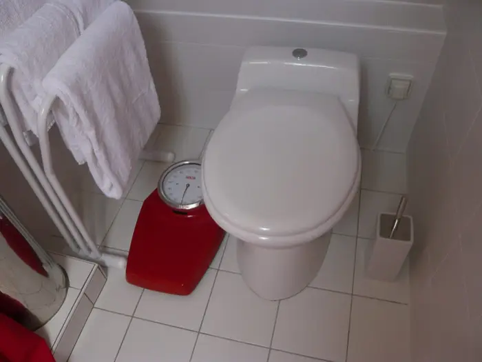 A white close-coupled toilet in a tiled bathroom beside a towel rail