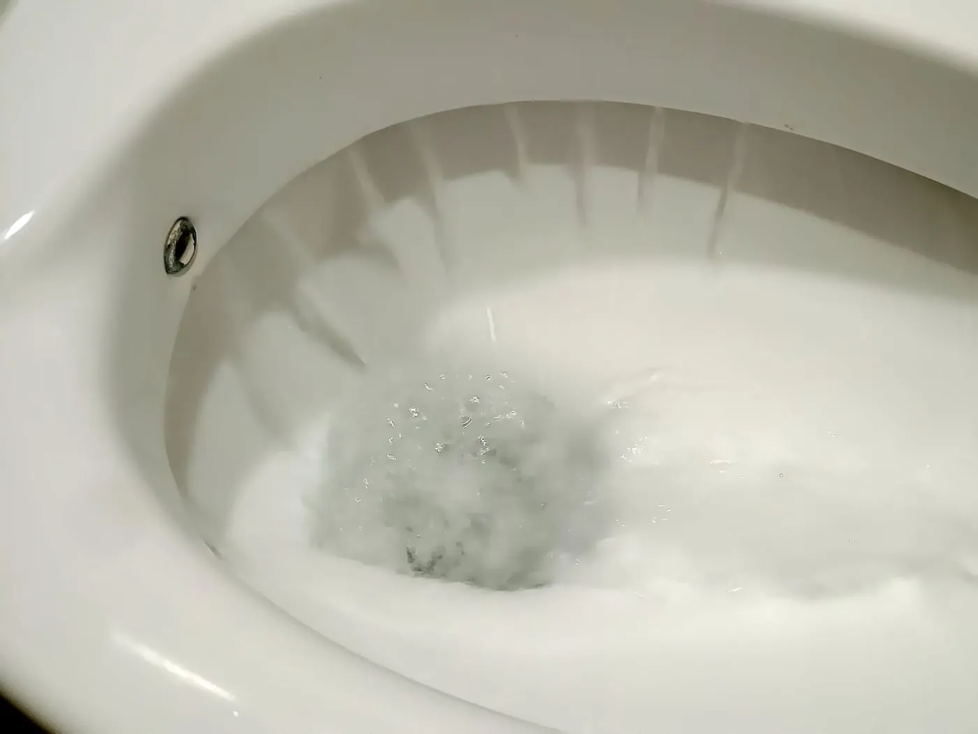 Water swirling in a white toilet bowl during a flush
