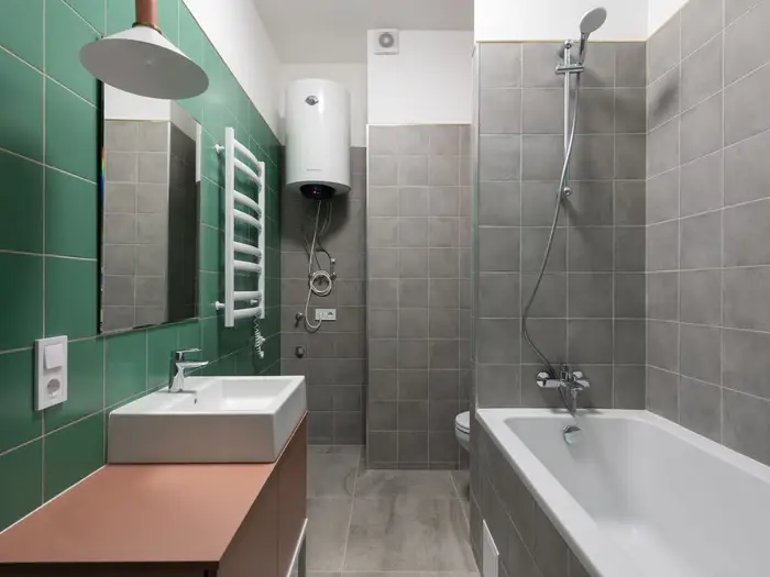A modern bathroom with a white hot water cylinder mounted high on the wall