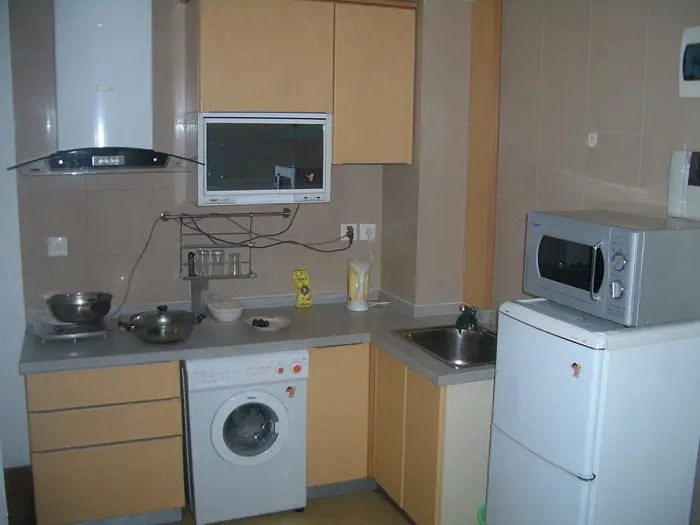 A washing machine fitted under the worktop of a small kitchen