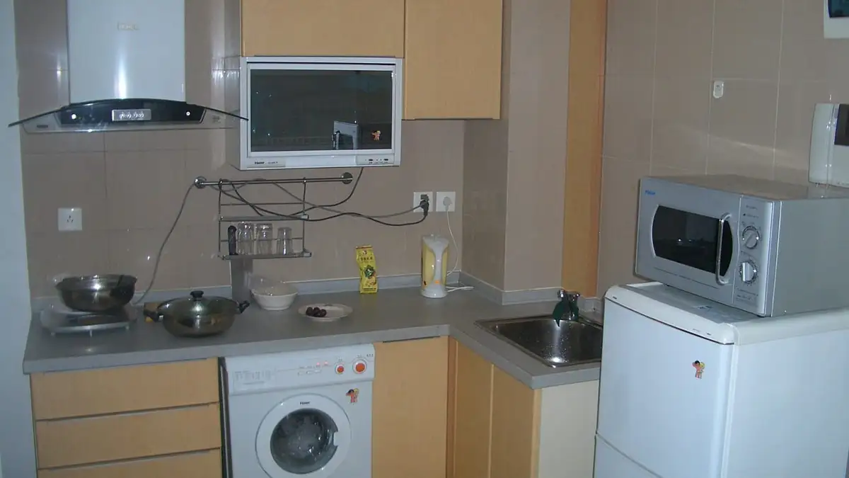 A washing machine fitted under the worktop of a small kitchen