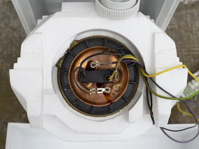 An under-sink water heater with its insulation removed, showing the heating element and wiring