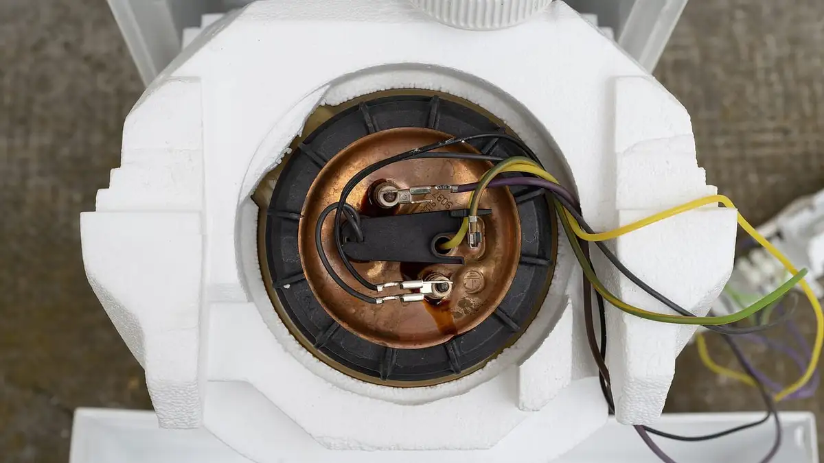 An under-sink water heater with its insulation removed, showing the heating element and wiring