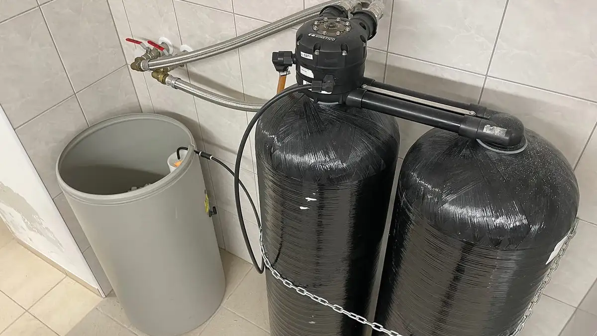 A twin-cylinder water softener with its salt tank in a tiled room