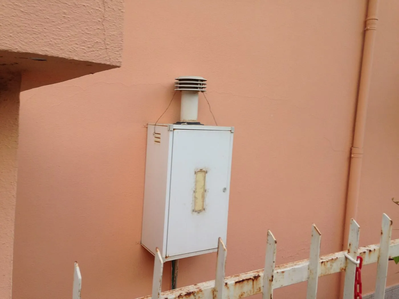 A white gas boiler with a flue mounted on an outside wall