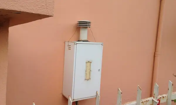 A white gas boiler with a flue mounted on an outside wall