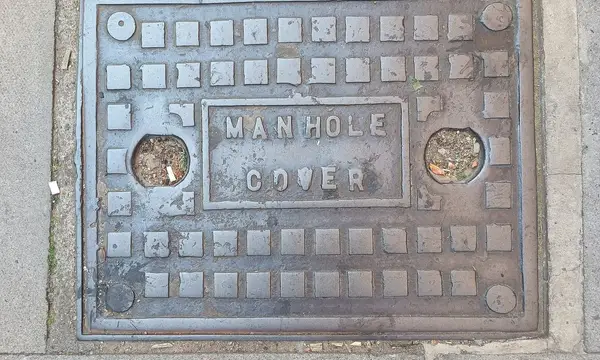 A cast-iron manhole cover in a London pavement