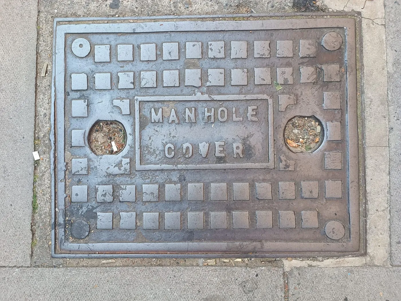 A cast-iron manhole cover in a London pavement