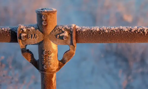 Frost on a metal pipe fitting at sunrise
